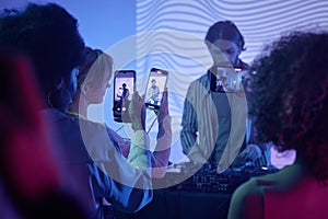 Young people filming DJ with smartphones
