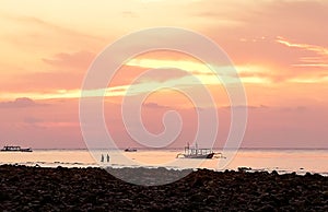 Young people fishing in a traditional way, next to a catamaran in Gili Trawangan, Lombok