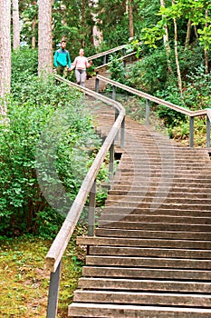 Young people go down the stairs, a long wooden staircase in the woods