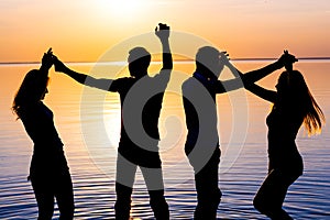 Young people, guys and girls are dancing couples at sunset background, silhouettes