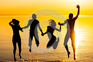 Young people, guys and girls, students are jumping against the sunset background