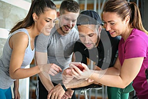 Young people in gym. Friends workout in gym and using smart phone.