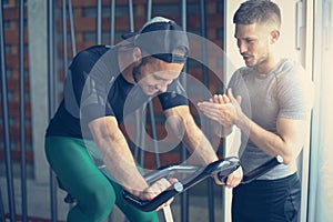 Young people in gym. Friends workout in gym and using smart phone.