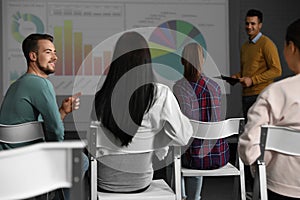 Young people having business training in room with projection screen