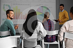 Young people having business training in room with projection screen