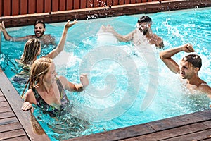 Young people having fun in exclusive pool party - Happy friends enjoying summer holidays in swimming pool