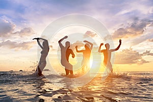 Young people having fun splashing water in the sea, friends