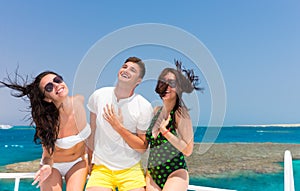 Young people having fun and standing on the yacht at a sunny sum