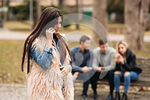 Young people having a good time in park. Male and female sitting on the bench and using phones