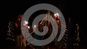 Young people having night beach party and dancing with sparklers