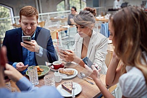 Young people having unsocial lunch in restaurant, using their cell phones and not talking to each other. social issues, victims of