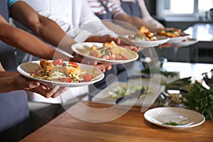 Young people holding plates with prepared dishes during cooking classes