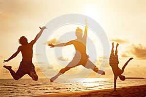Young people jumping on the beach with sunset