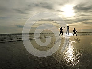 Young people jumping on the beach with sunset background