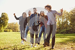 Young people laugh while standing in a park in spring.