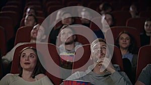 Young people laughing at cinema theater. Young people watching amusing comedy