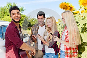 Young people listening guy playing guitar friends drinking beer bottles outdoor countryside