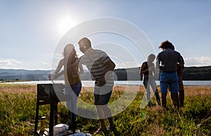 Young people making BBQ at lakeside meadow