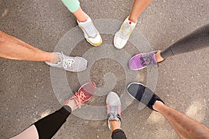 Young people making circle and showing their sports shoes outdoors