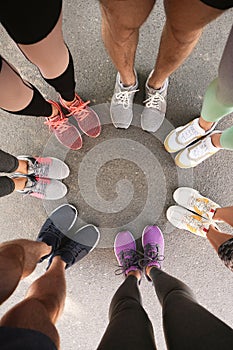 Young people making circle and showing their sports shoes outdoors