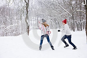 Young people play snowballs in winter forest