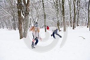 Young people play snowballs in winter forest