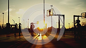 Young people playing basketball at sunset