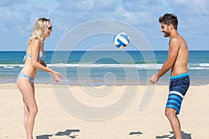 young people playing beach volley together by sea