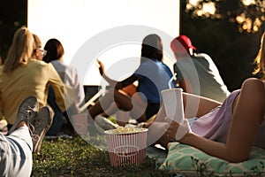 Young people with popcorn and drink watching movie in open air cinema