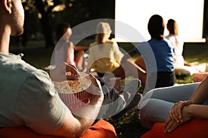 Young people with popcorn watching movie in open air cinema. Space for text