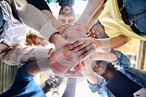 Young people putting their hands together.