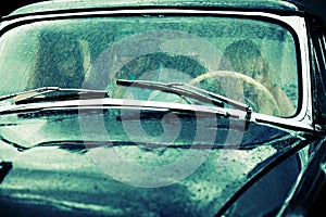 Young people driving retro car in the rain