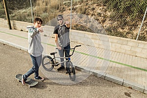 Young people riding bikes and skateboards in the city. Modern people with a skate and a bmx down the street