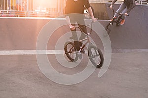 Young people riding a Bmx bike in a skate park in the background of the sunset. Bmx Concept. Bmx Bicycle Training