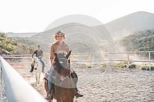 Young people riding horses inside corral - Wild couple having fun in equestrian ranch  - Training, culture, passion, excursion,