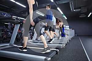 Young people running on treadmill in gym