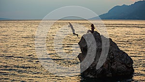 Young people`s jumping to the water from big stone