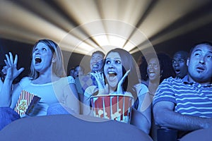 Young People Screaming While Watching Horror Movie In Theatre