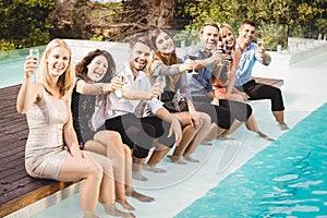 Young people sitting by swimming pool