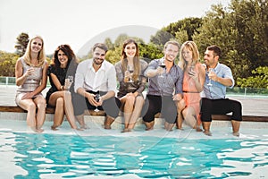 Young people sitting by swimming pool