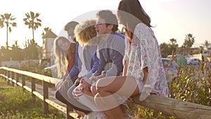 Young People Sitting On Wooden Fence.