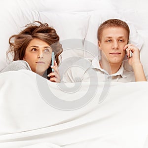Young People with smartphones in bed