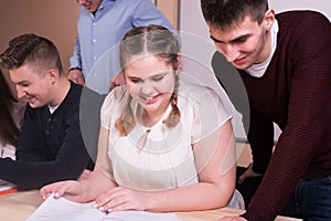 Young people studying with books on white desk.