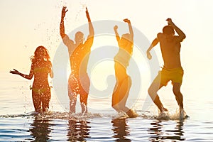 Young people swimming at sunrise party on the beach - Group of multi race friends having fun on vacation - Friendship and holidays