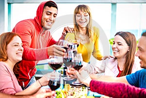 Young people toasting red wine at dinner party on multicolored clothes - Happy drunk friends having fun together