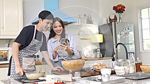 Young people use smartphones to take pictures while cooking with excited and happy faces.
