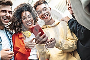 Young people using smart mobile phone device outdoors - Happy teenagers having fun together watching video stories on social media