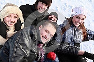 Young people by winter day lie on snow
