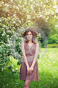 Young perfect woman with brown shoulder-length hair haircut. Beautiful model girl in summer dress and fedora hat