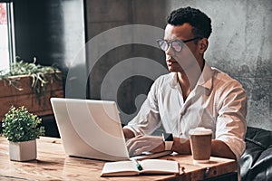 Young perfectionist. Handsome young African man in eyewear worki